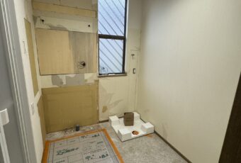 施工途中の様子です。既存の洗面台、袖壁、壁紙を撤去し、洗濯機の位置を変えたところ。